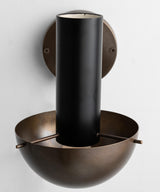 Close-up of brass wall lamp showing cylindrical upper form, solid brass wall mount, and hand-finished surface detailing.