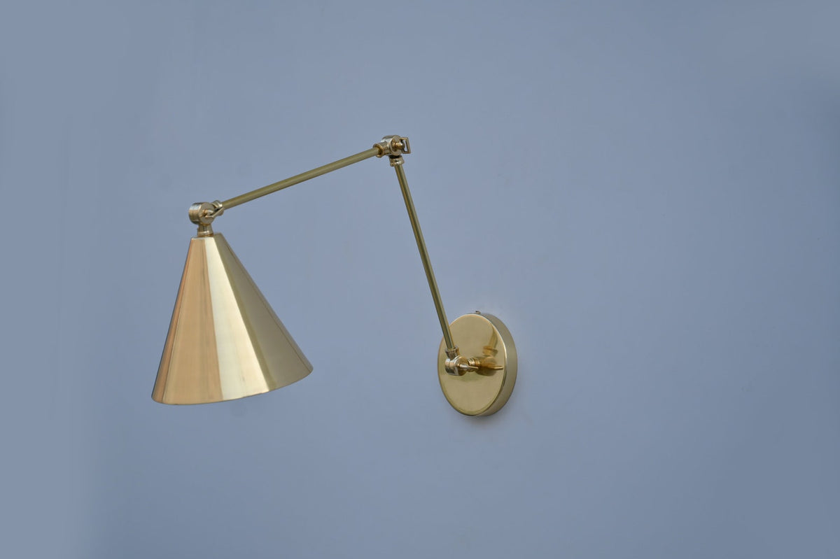 Brass wall light with conical shade, glowing warm ambiance in modern interiors