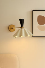 Solid brass wall sconce with sculptural fluted shade installed in modern living room interior providing warm ambient lighting