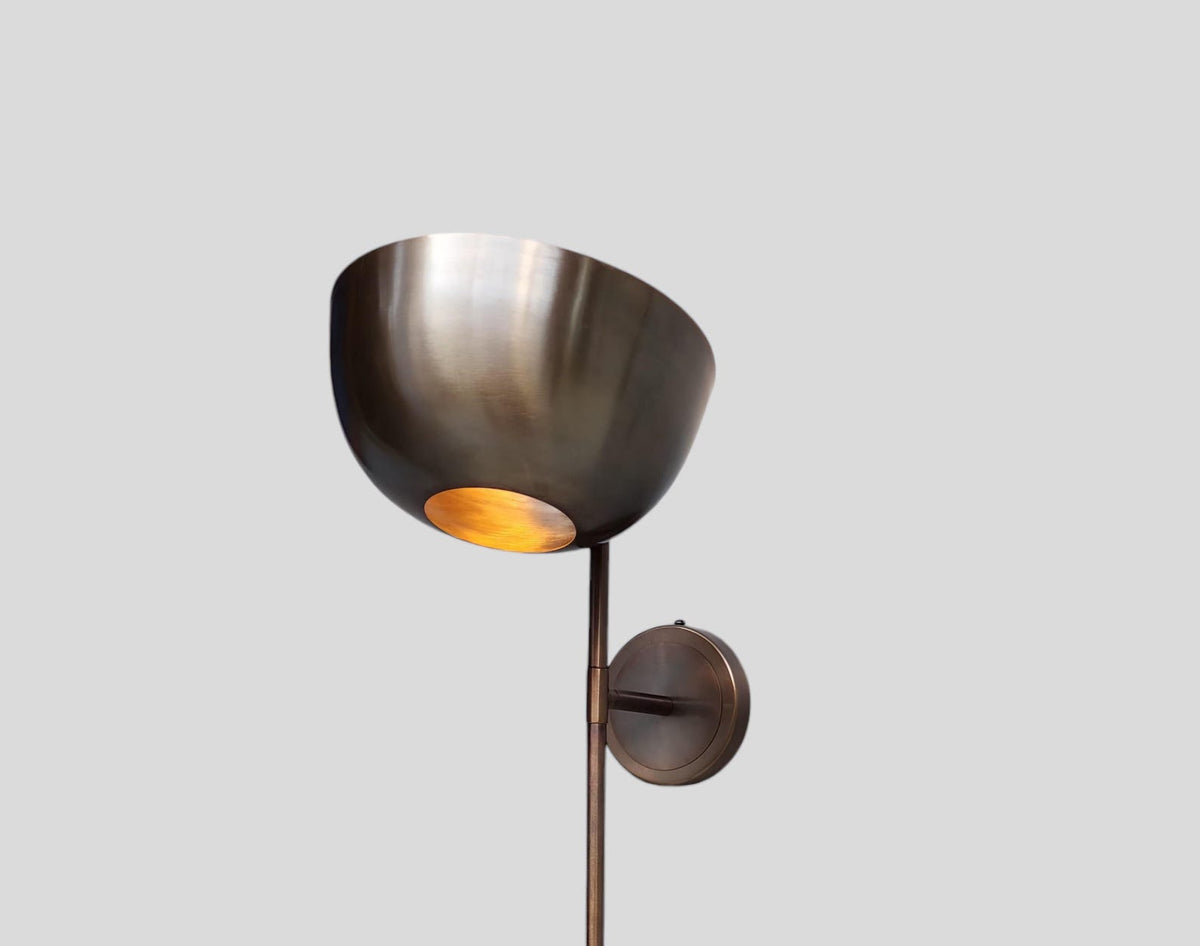 Close-up of brass wall light sconce bowl shade highlighting brushed finish