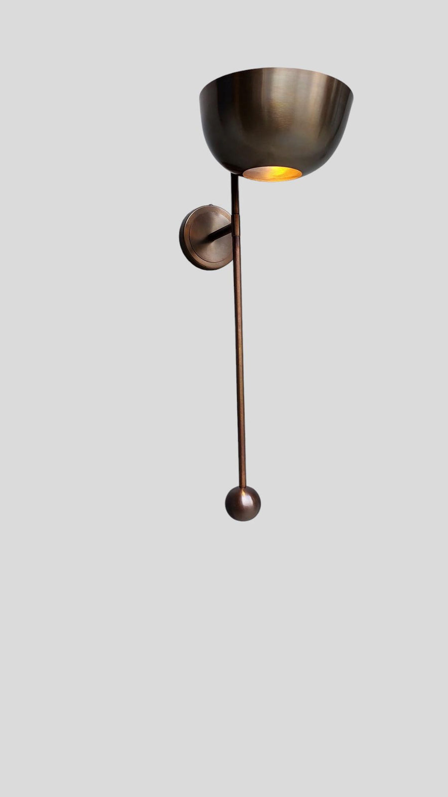 Front view of modern brass wall light sconce with bowl shade and rod design