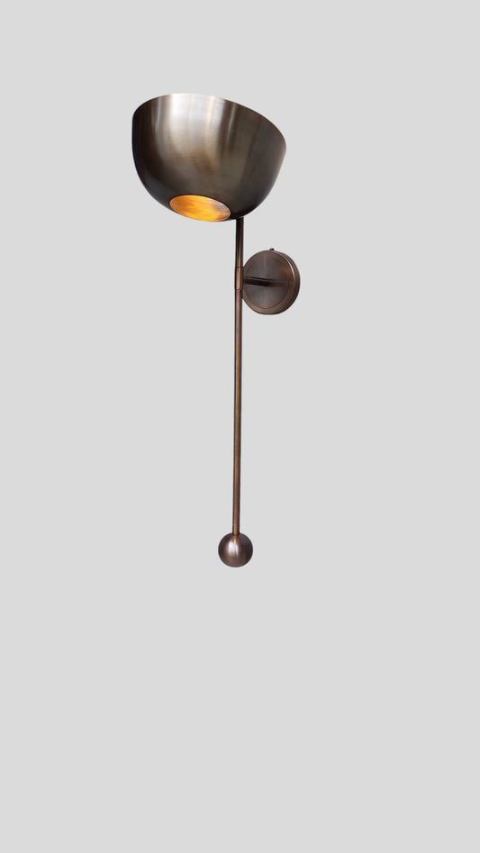 Side angle of handcrafted brass wall light with bowl shade and minimalist rod design