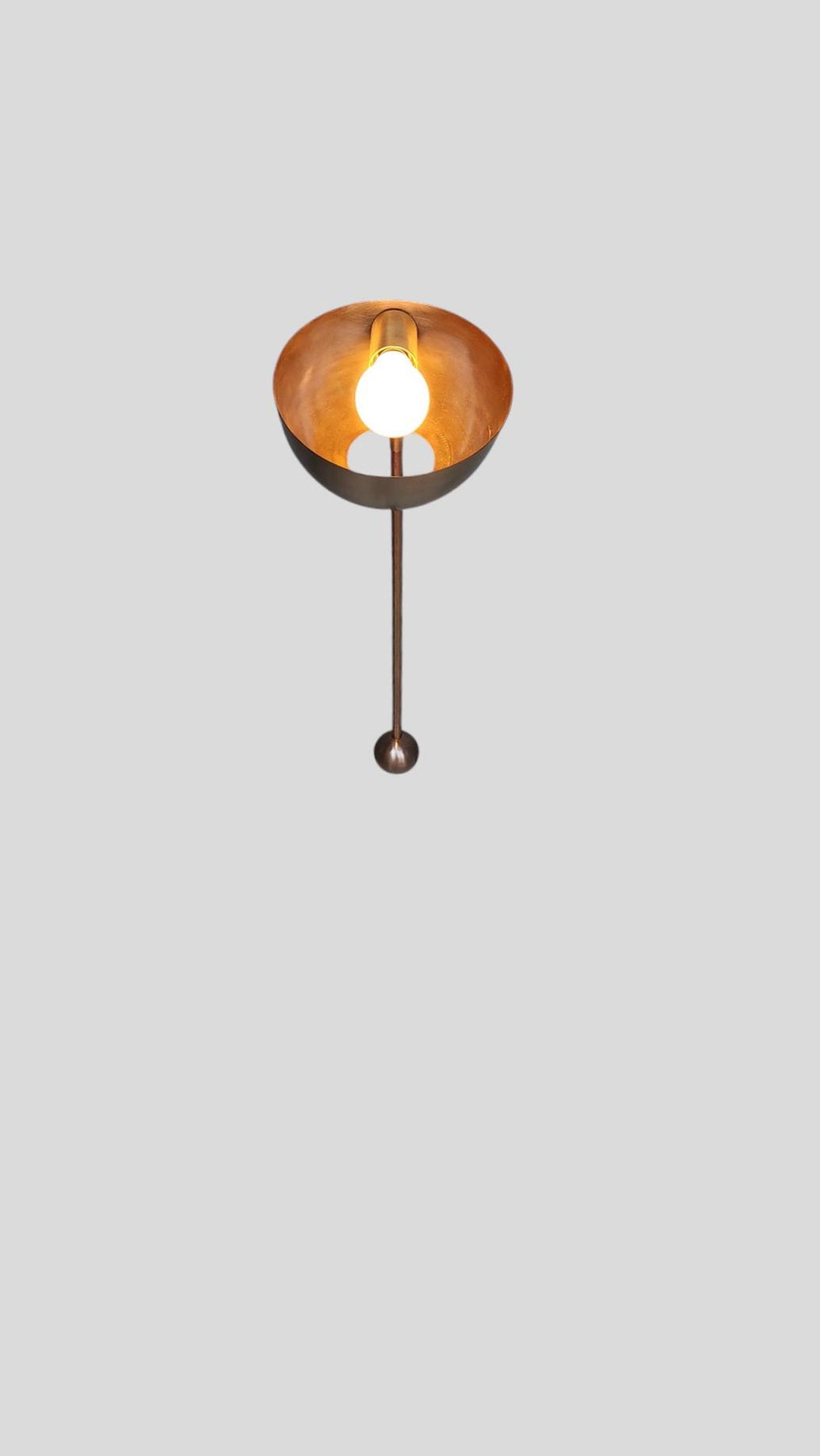 Top angle of brass wall lamp showing warm interior glow and industrial style