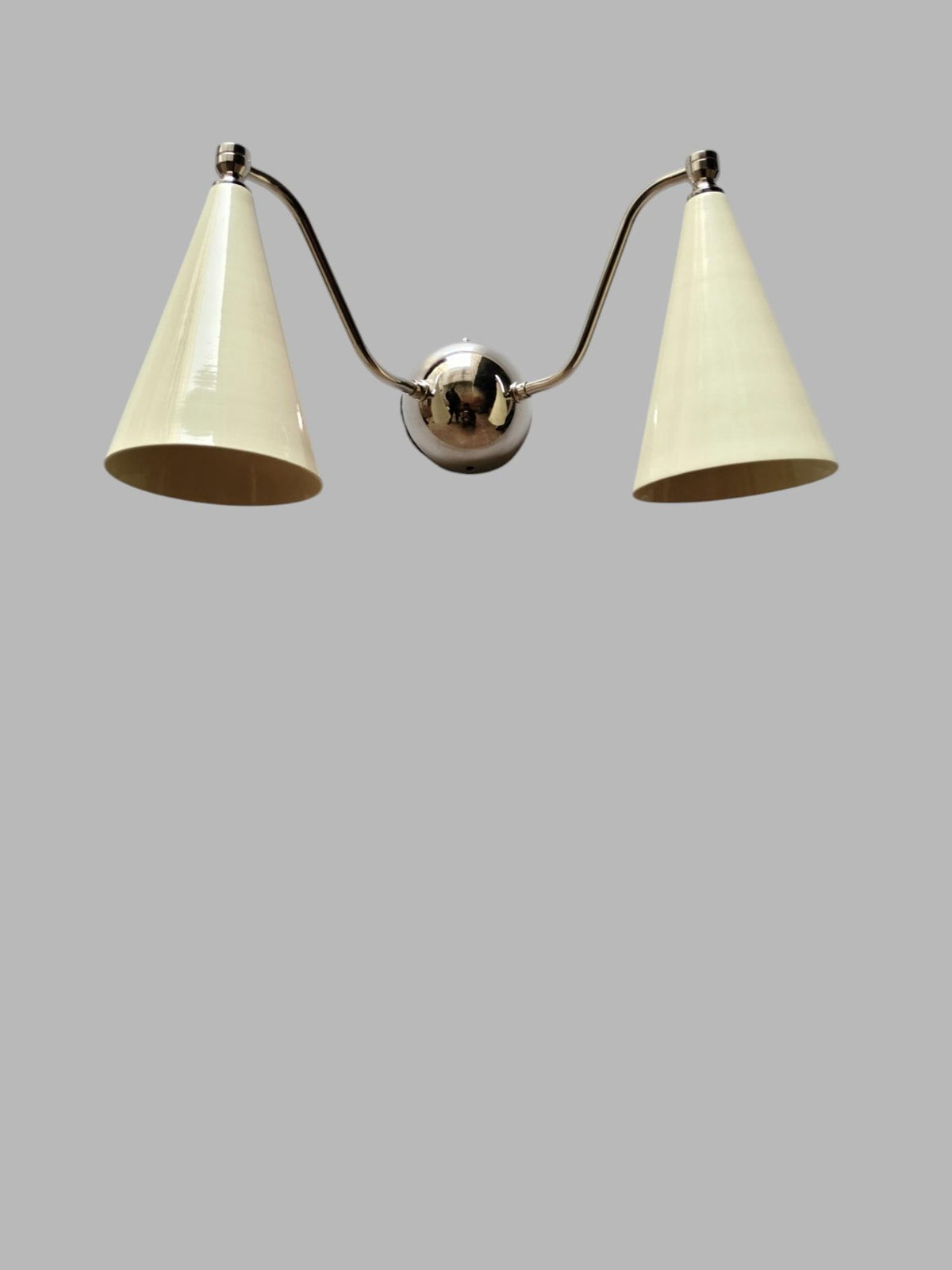 Modern brass wall light with dual cone shades in white finish, handcrafted sconce for elegant interiors.