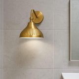 Modern brass dome wall sconce installed in bathroom setting with tiled wall and soft warm lighting.