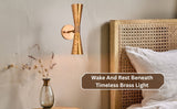 Brass double cone wall sconce mounted beside bed with cane headboard in a cozy bedroom setting