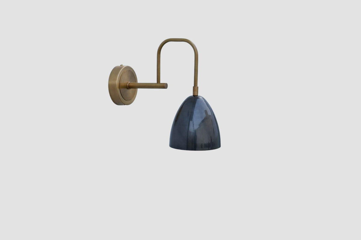 Elegant brass wall sconce with curved arm and glossy blue shade, designed for contemporary and industrial spaces