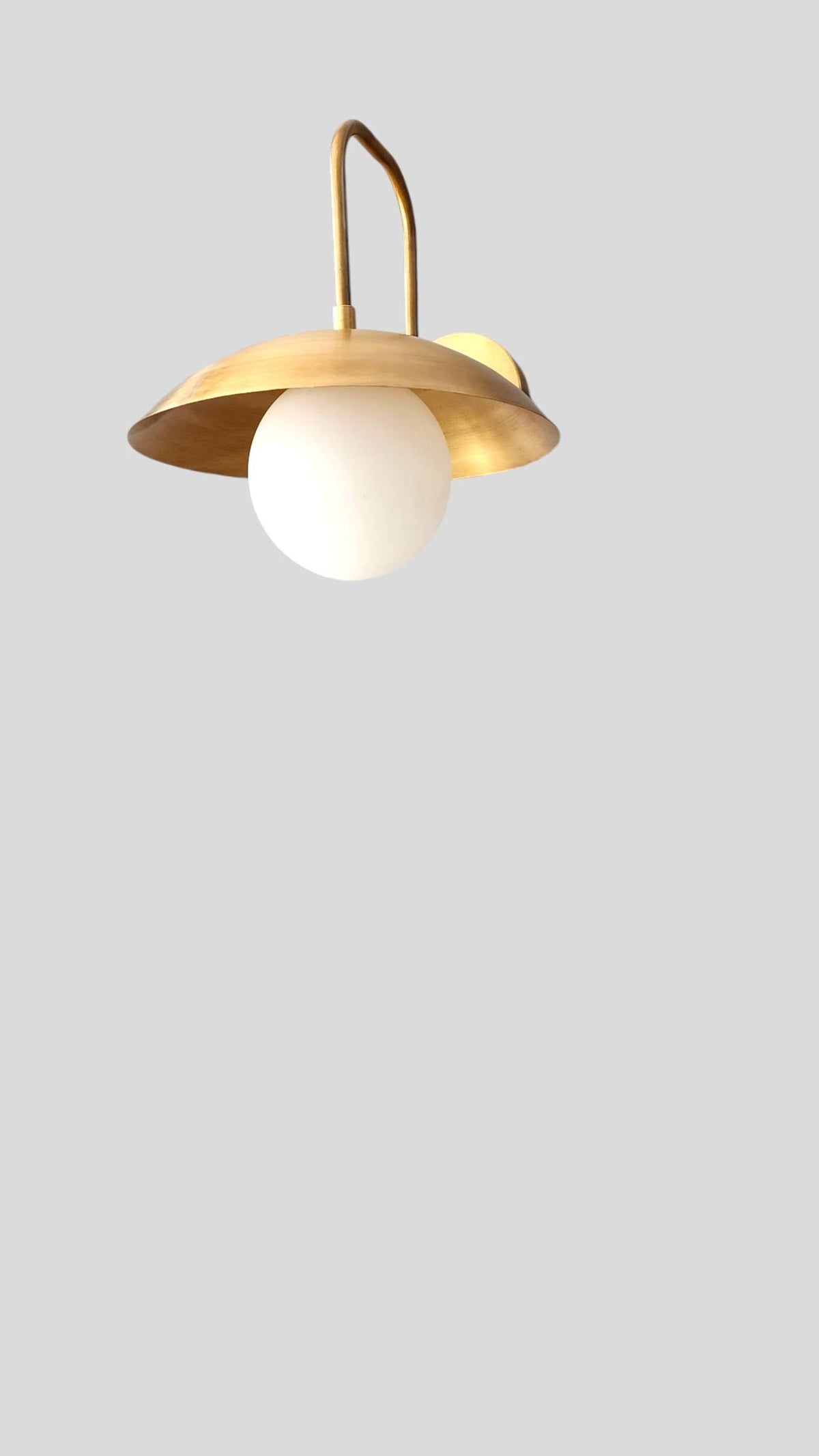 Bottom view of handmade brass wall sconce with round frosted globe diffuser