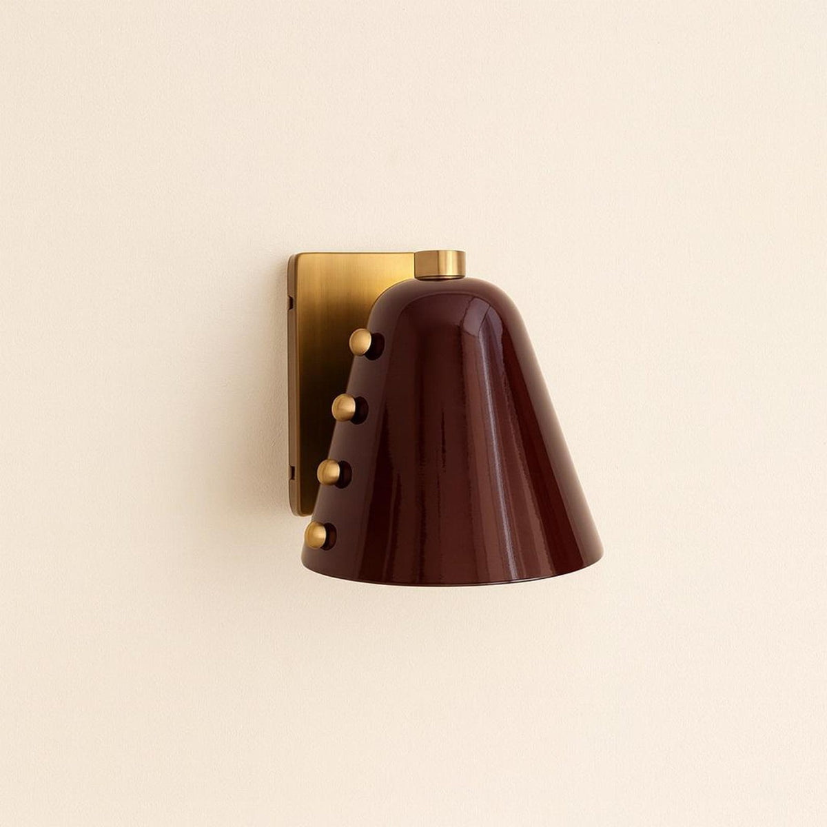 Side view of burgundy cone wall sconce with decorative brass studs and square brass backplate