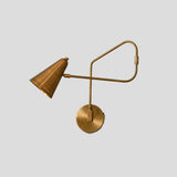 Handmade brass wall sconce with adjustable swing arm and cone shade, left side angle view