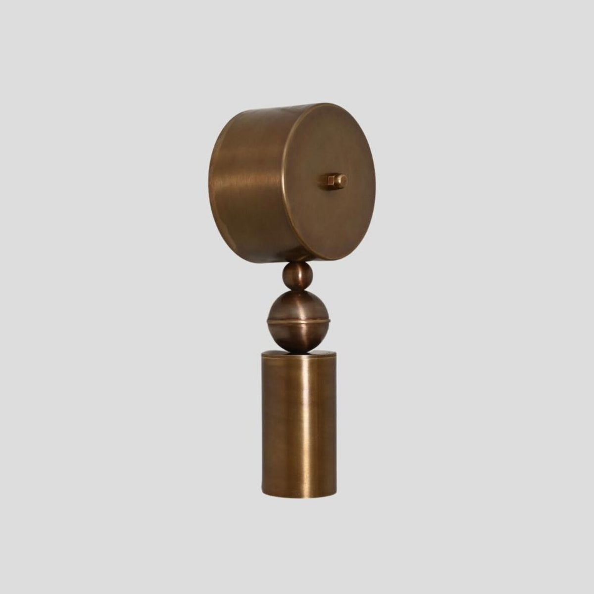 Custom brass wall sconce with cylinder and sphere detailing, minimalist geometric wall light oblique view