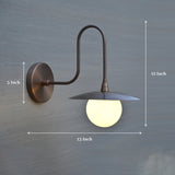 Brass wall sconce light with 12-inch height and 13-inch width, curved arm design and round glass globe shade.