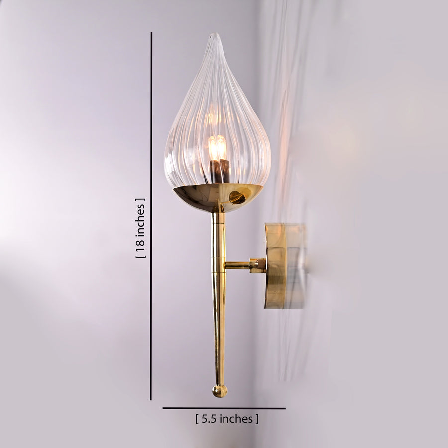 Polished brass wall sconce with teardrop glass shade mounted on white marble wall