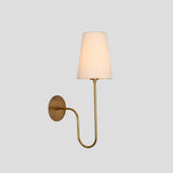 Handmade brass wall sconce with elegant curved arm and tapered fabric shade, designed for modern and classic interiors.