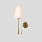 Stylish brass wall lamp with round backplate, elegant curved arm, and soft glowing fabric shade for cozy interiors.