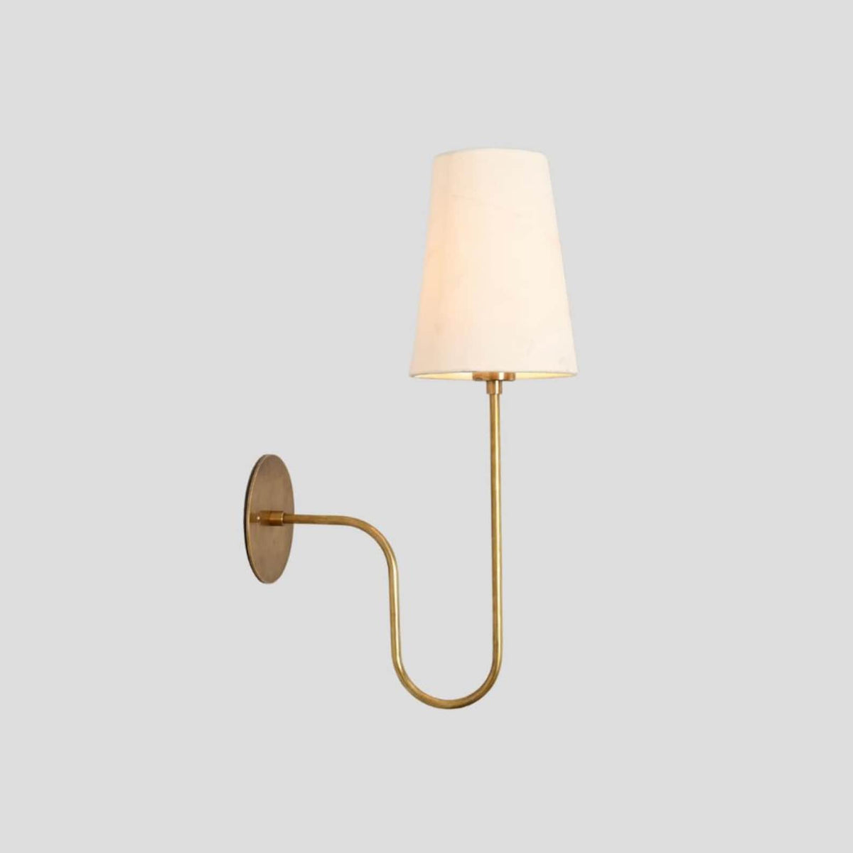 Handmade brass wall sconce with slim frame and fabric shade, perfect for adding ambient lighting to modern and traditional interiors.
