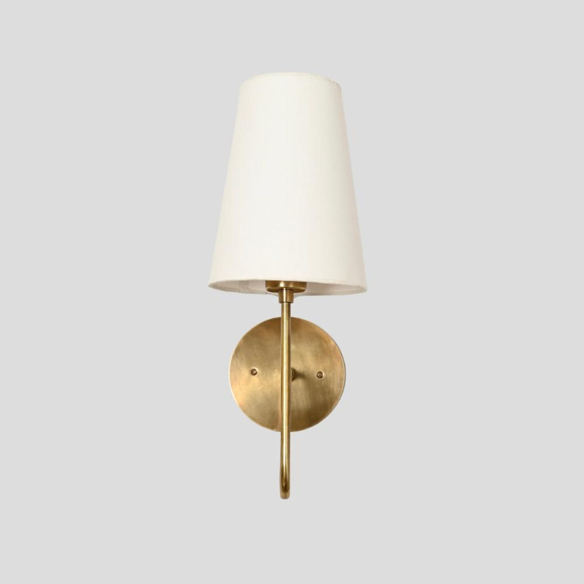 Modern brass wall sconce with tapered fabric shade, front view highlighting minimalist design