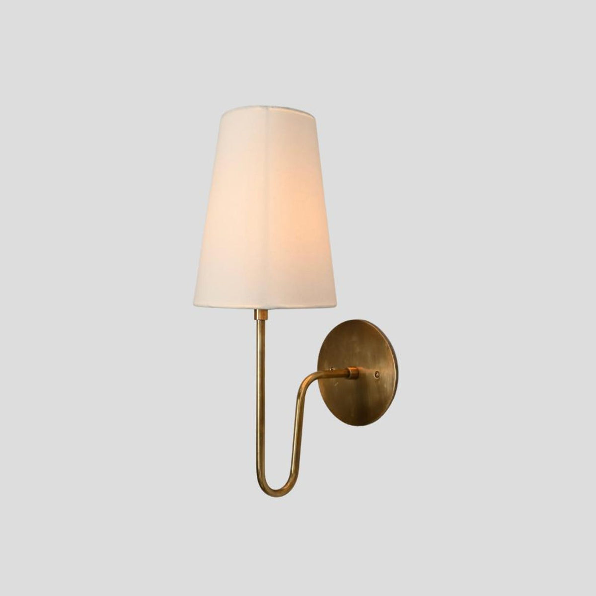 Elegant brass wall sconce with fabric shade, side profile showcasing curved arm and round backplate