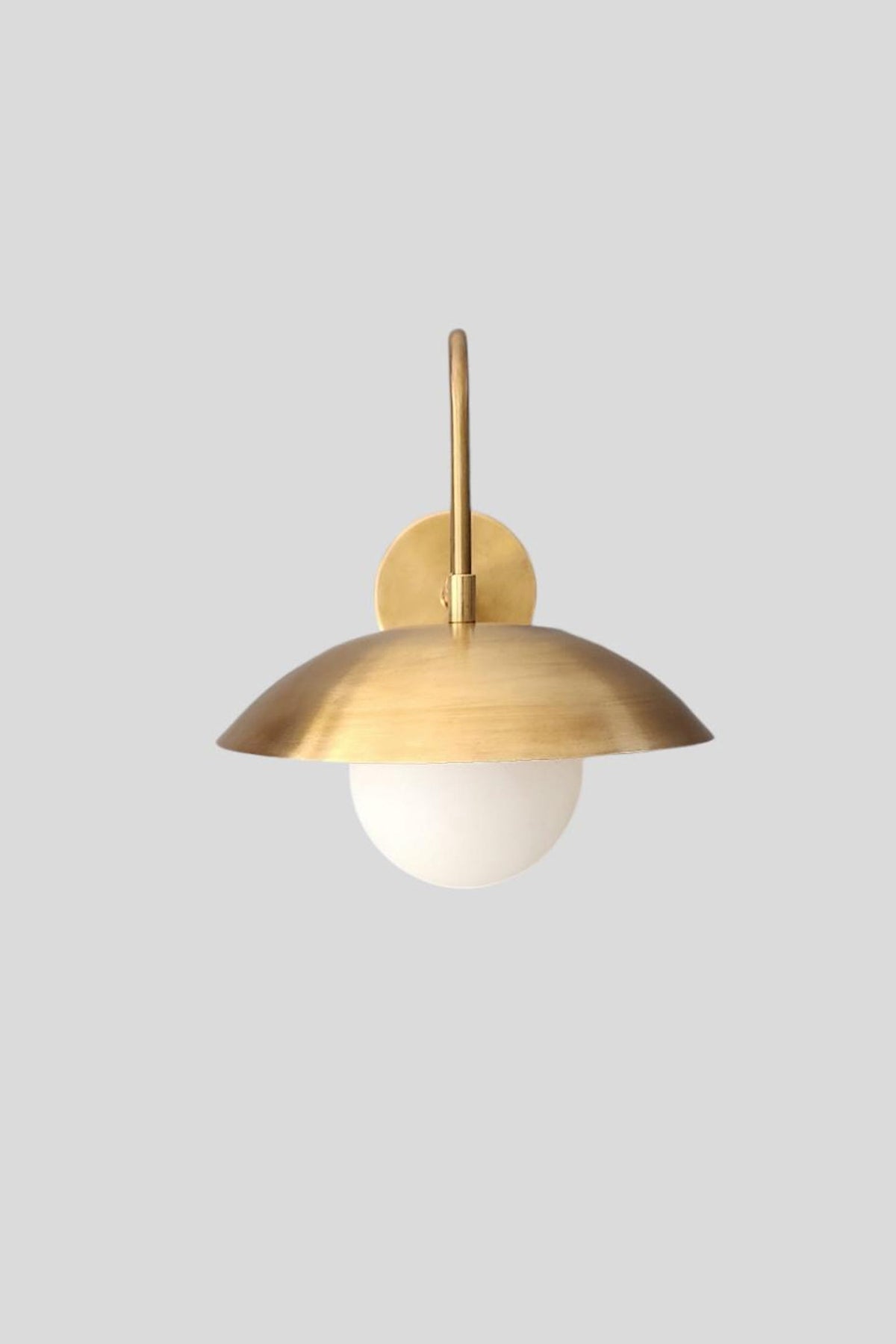 Center front view of brass wall sconce with dome shade and frosted glass globe bulb