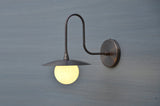 Handmade brass wall sconce with globe shade and curved arm design, industrial modern wall light for home interiors