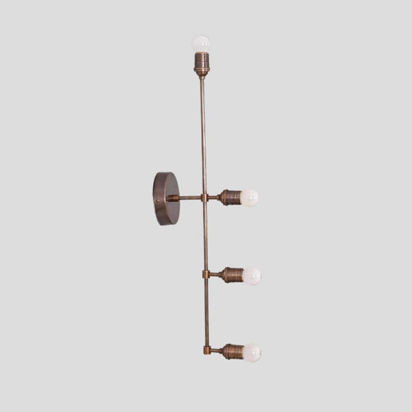 Handmade brass wall sconce with vertical linear design and exposed bulb holders, crafted by Brass Leaf Studio for modern and industrial interiors.