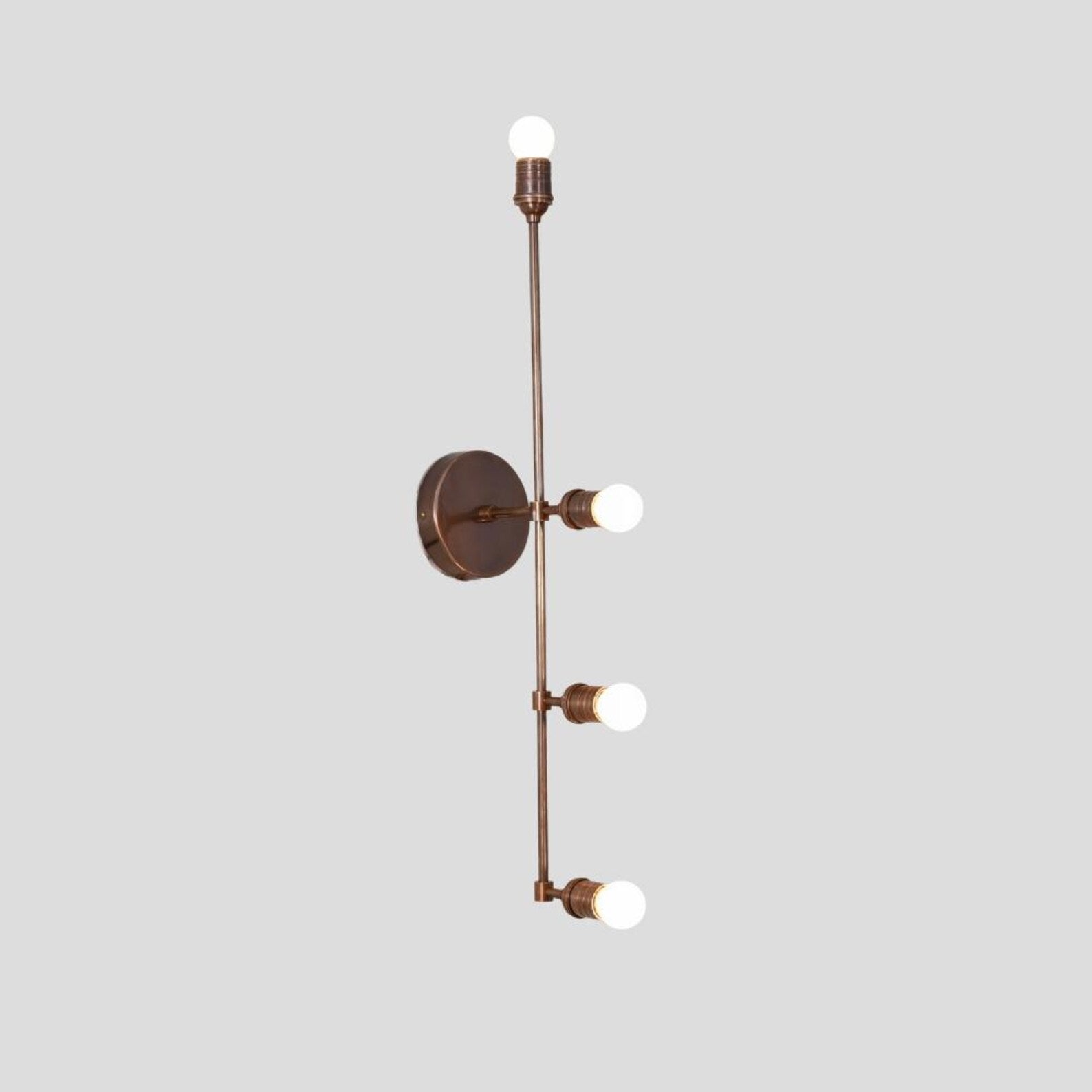 Vertical brass wall light with four exposed bulbs in a linear arrangement, perfect for hallways, bedrooms, and contemporary living spaces.