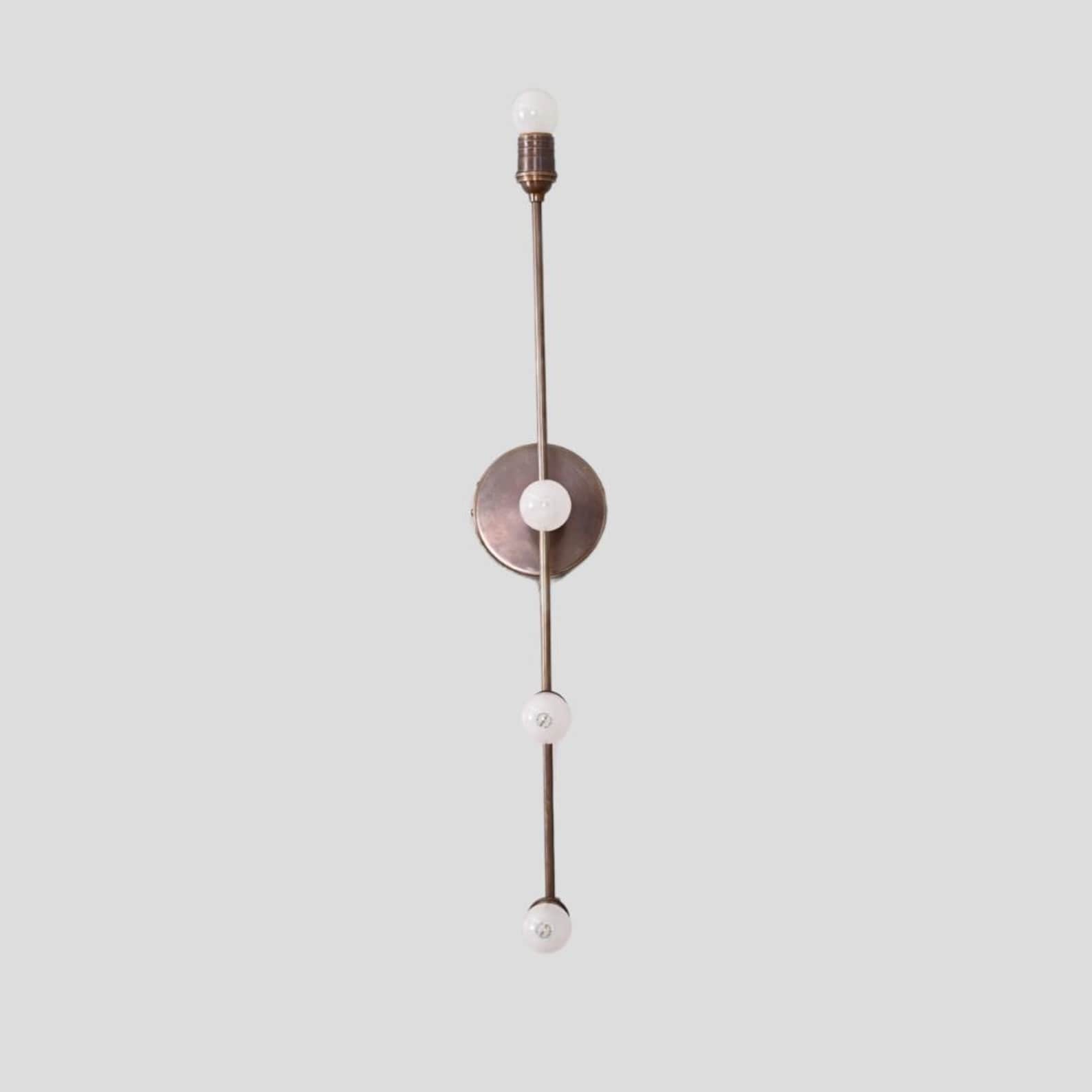 Industrial-style linear brass wall lamp with minimalist vertical design and multiple bulb sockets, ideal for modern homes, cafes, and boutique interiors.