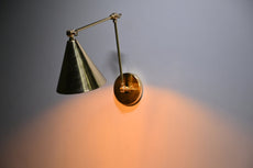 Handmade brass wall sconce with cone shade casting warm downward glow