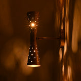 Side view of brass wall sconce glowing warmly against patterned wall