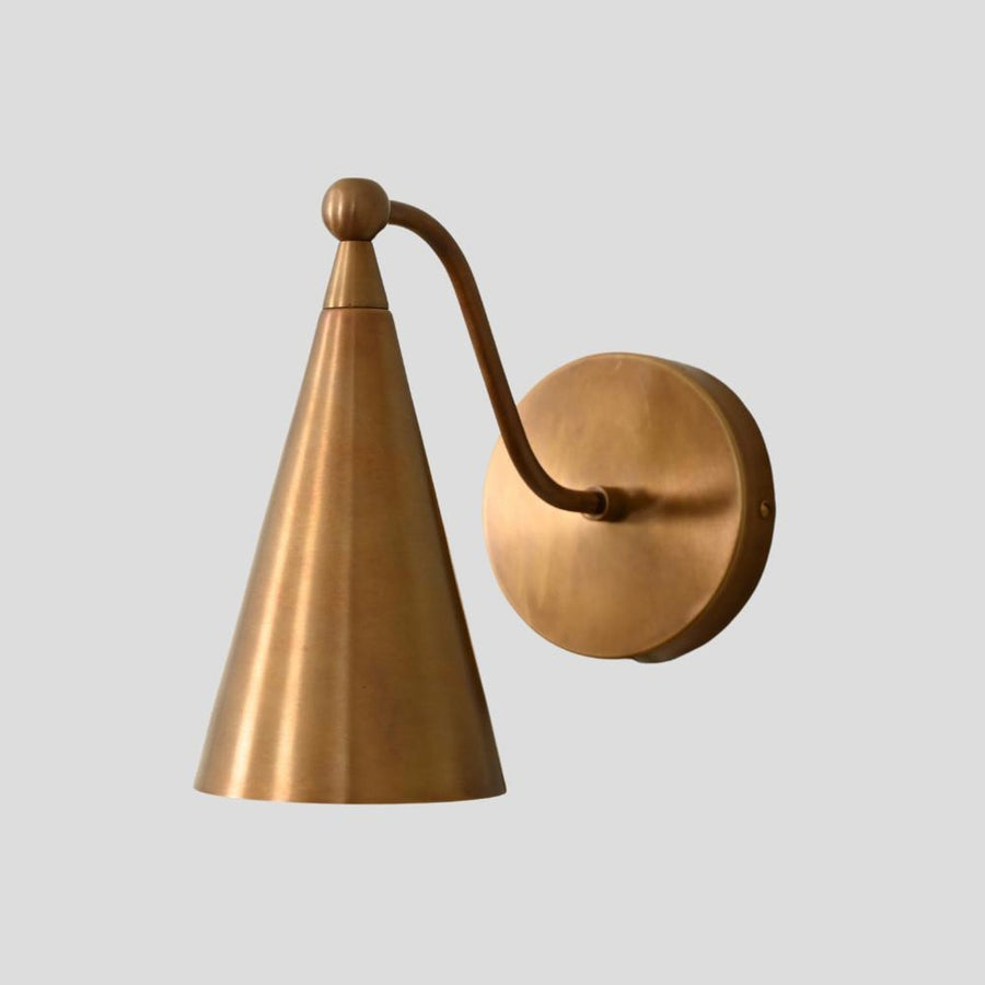 Handmade brass wall sconce with cone shade, minimalist industrial design by Brass Leaf Studio, side angle view.