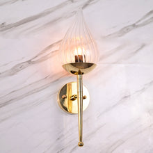 Polished brass wall sconce with teardrop glass shade mounted on white marble wall