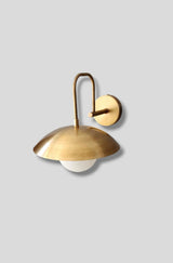 Side angle view of brass wall sconce lamp with dome shade and frosted glass globe