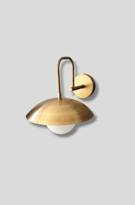 Side angle view of brass wall sconce lamp with dome shade and frosted glass globe