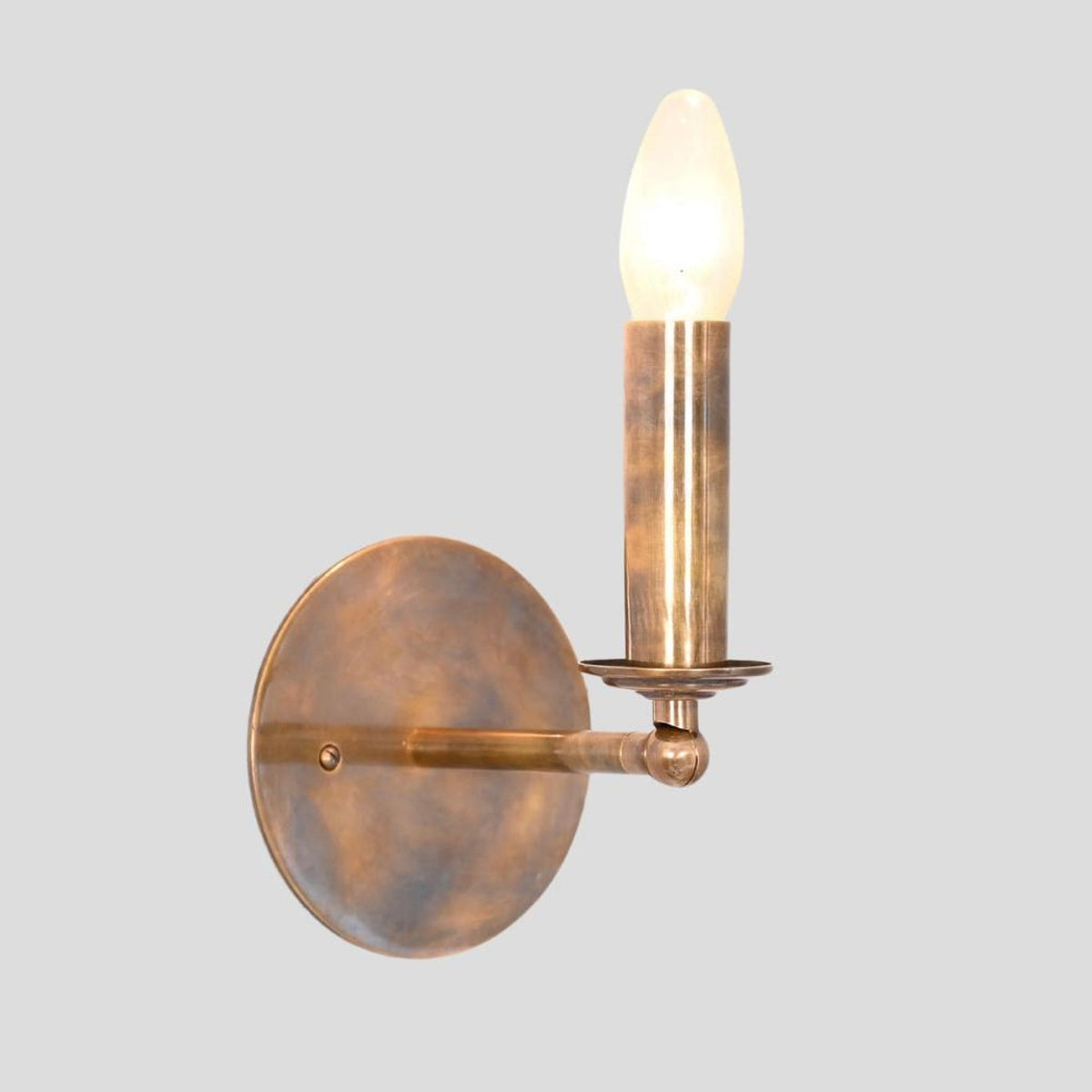 Angled view of handcrafted brass candle style wall sconce with round base – Brass Leaf Studio