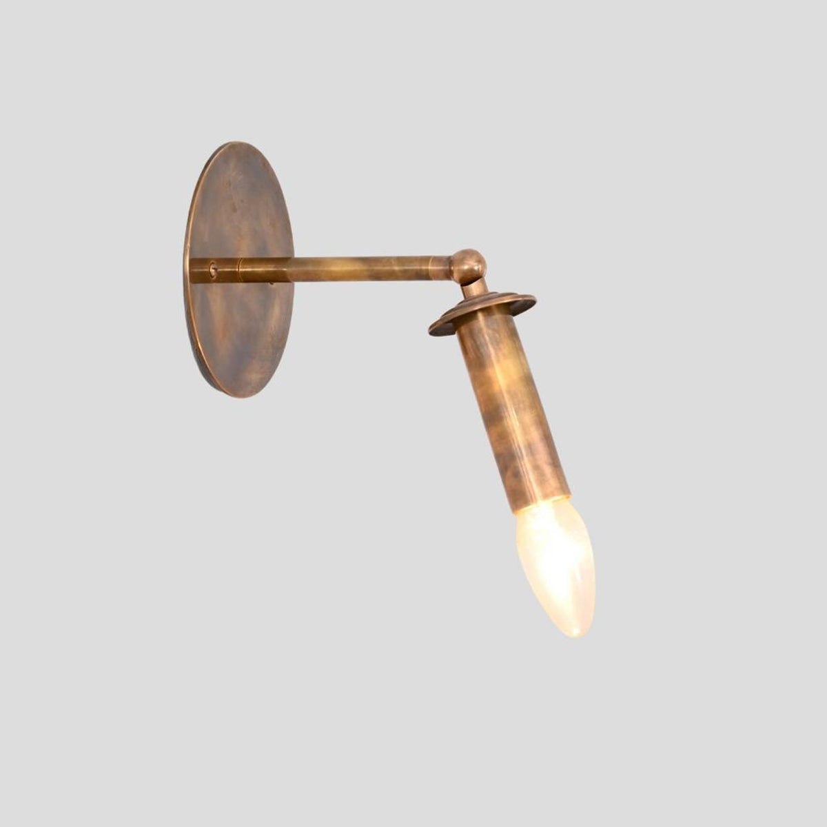 Tilted side view of vintage brass candle style wall light with glowing bulb – Brass Leaf Studio