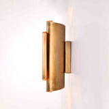 Brass wall sconce creating warm upward, downward, and side lighting effect on interior wall
