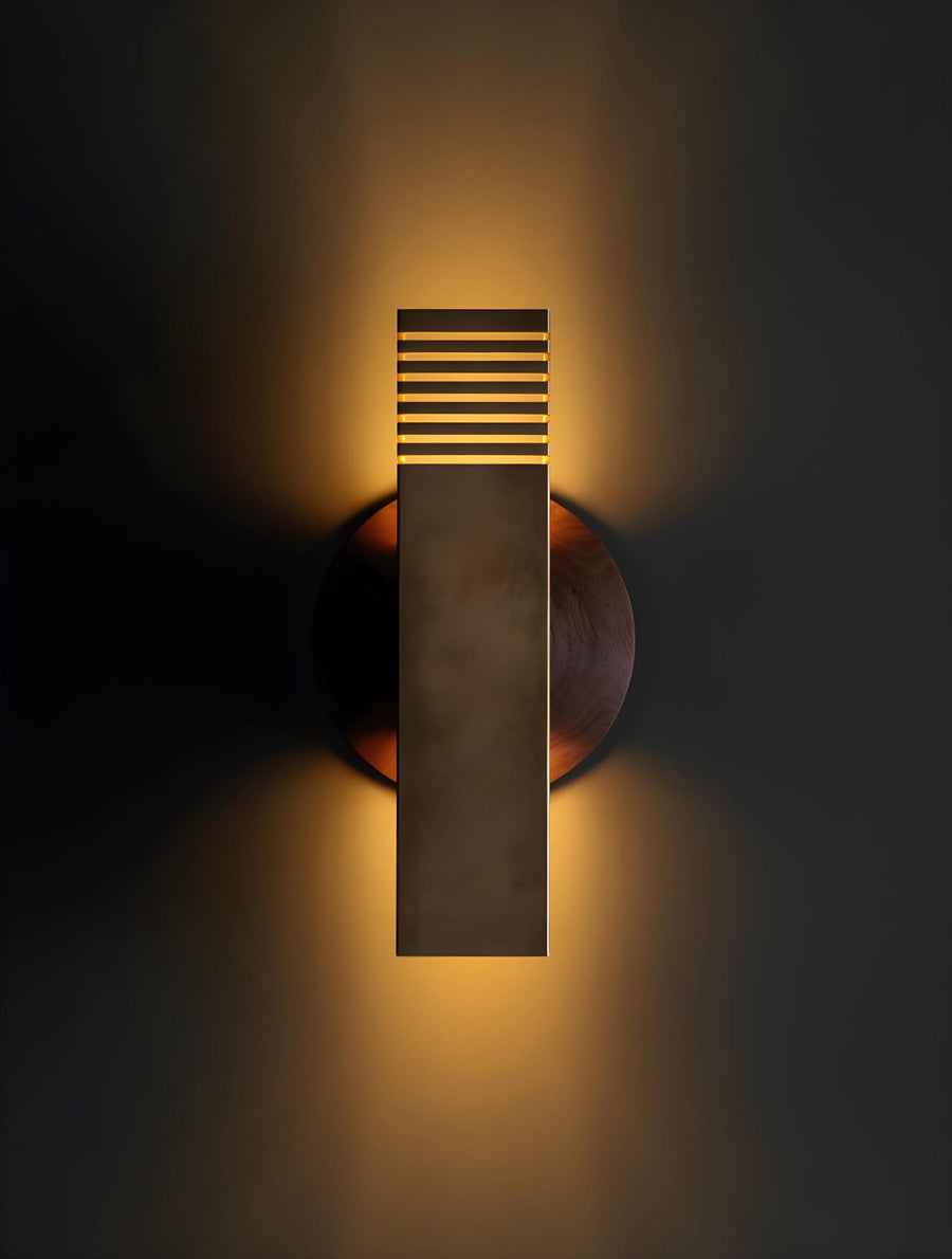 Modern brushed brass wall sconce with rectangular body and slotted top design mounted on dark wall