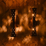 Brass double cone wall sconces illuminated on patterned wall with soft warm glow