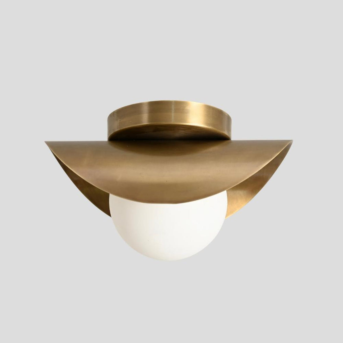 Artistic brass flush mount ceiling light with curved wave detail and white opal globe shade
