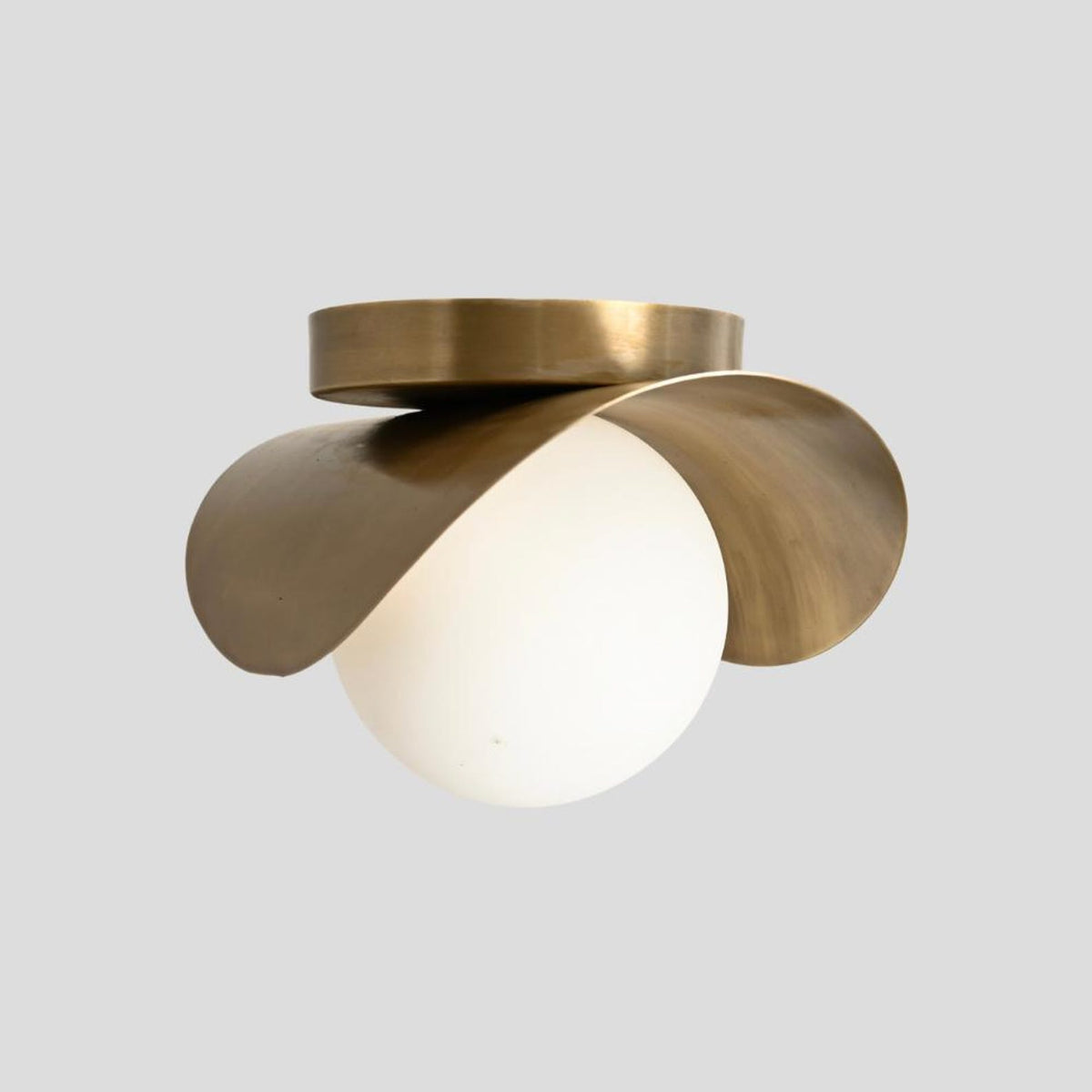 Contemporary brass flush mount ceiling light featuring sculptural curves and opal glass globe shade