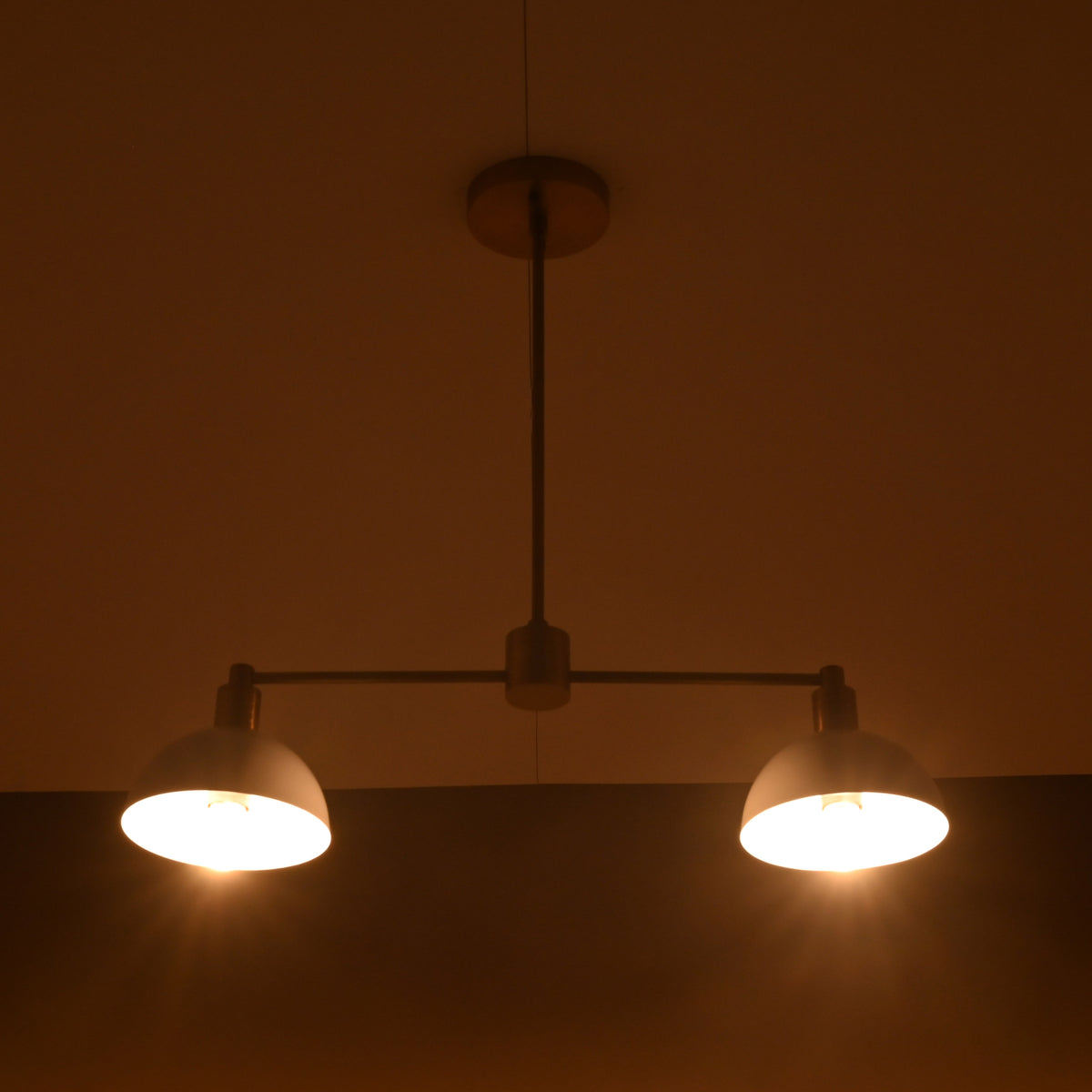 Warm nighttime ambience created by minimalist brass and white dome ceiling pendant