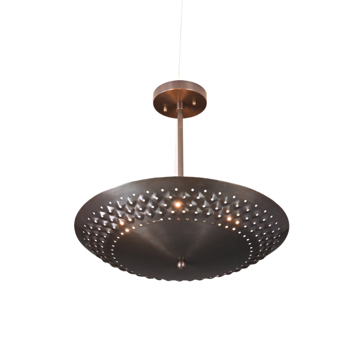 Close-up view of a suspended brushed brass disc chandelier with perforated pattern