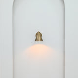 Compact brass patina wall sconce installed in an elegant hallway with warm directional lighting