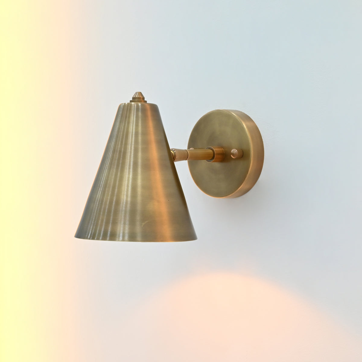 Bruges tiltable cone wall sconce used as focused reading light beside a lounge chair