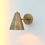 Bruges tiltable cone wall sconce used as focused reading light beside a lounge chair