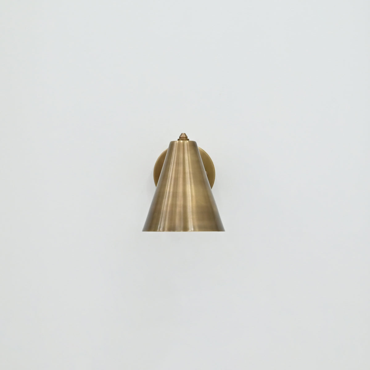 Solid brass Bruges wall sconce with minimalist cone shade and warm patina finish