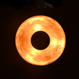 Bottom glow of brushed brass bowl pendant casting warm ambient light in dark setting.