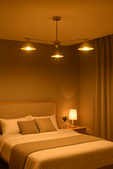 Warm-lit brushed brass chandelier with cone shades installed above a modern bed, creating cozy and elegant bedroom lighting ambiance