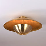 Close-up of brushed raw brass disc ceiling light showing smooth lacquered surface and warm golden tone