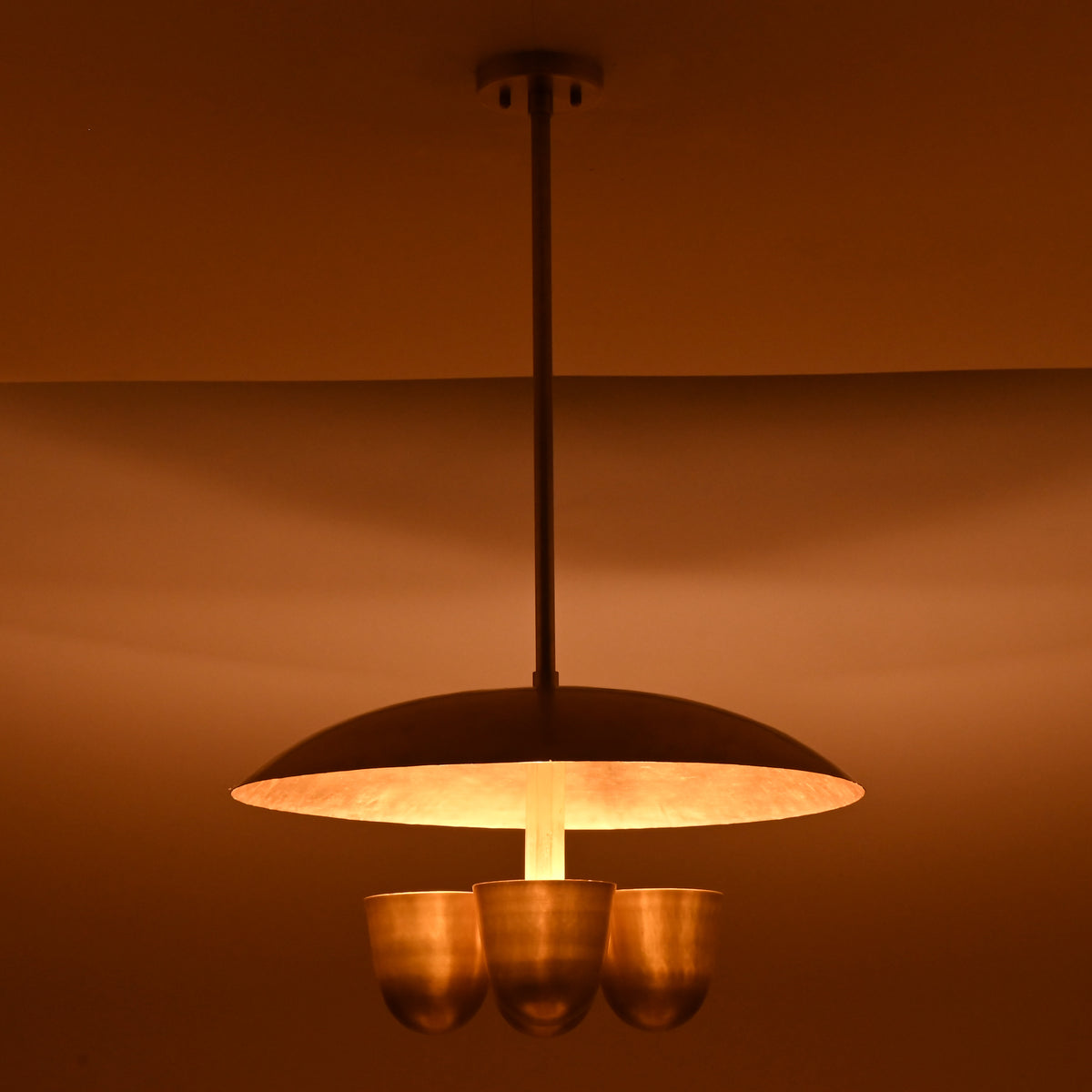 Moody lighting effect from brushed brass disc chandelier with four bowl shades, luxury handcrafted ceiling light by Brass Leaf Studio